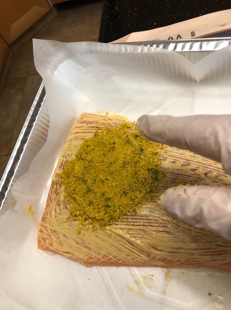 Pressing breadcrumb topping on salmon