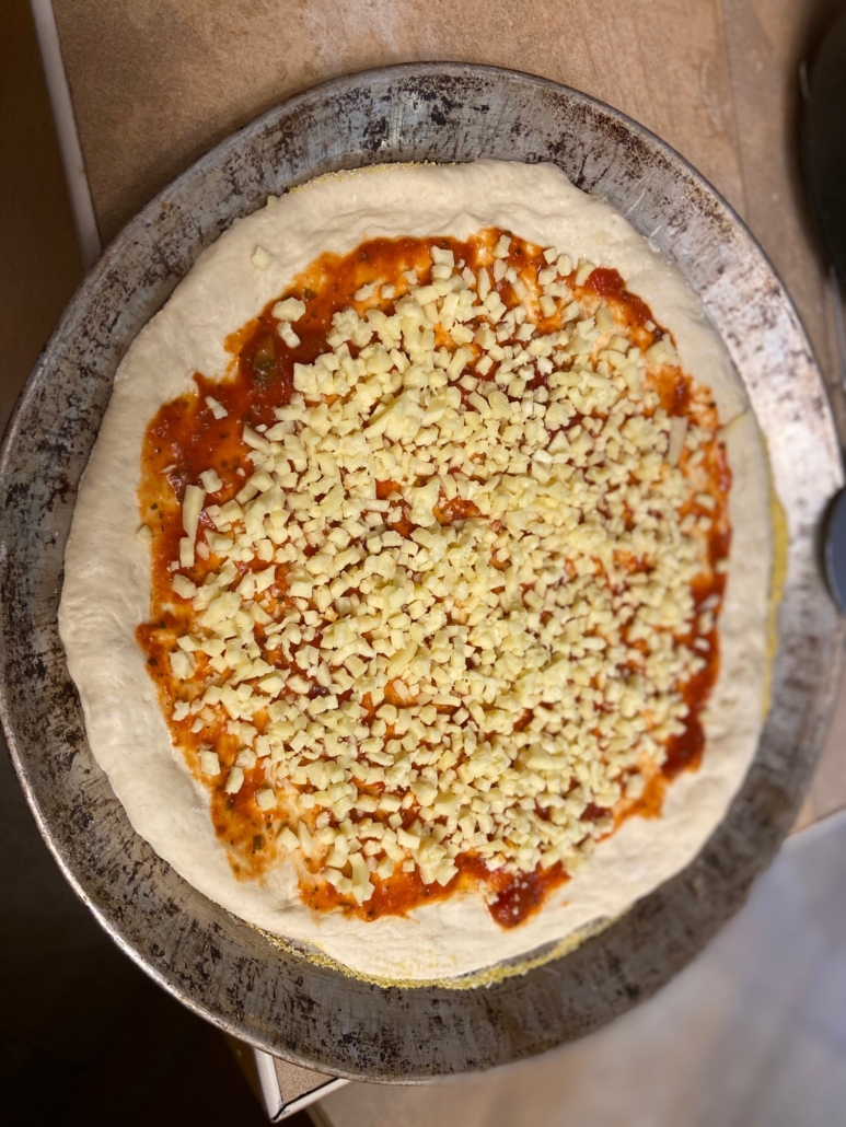 Pizza dough with sauce and cheese