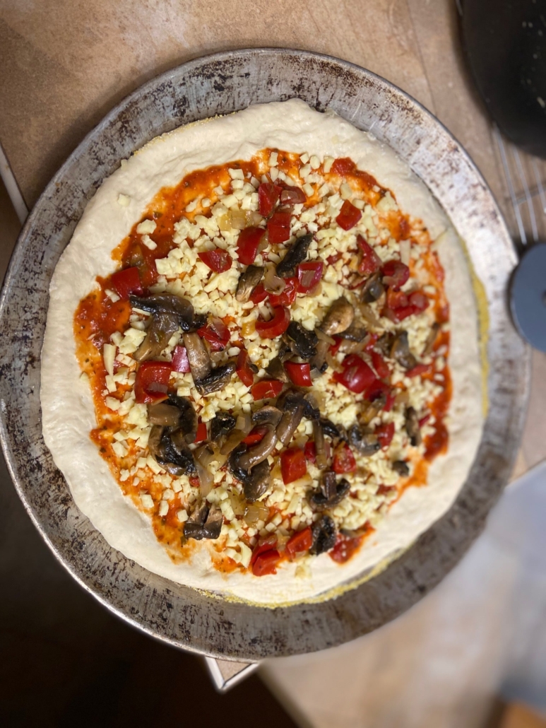 Pizza dough with sauce and cheese and sauteed veggies