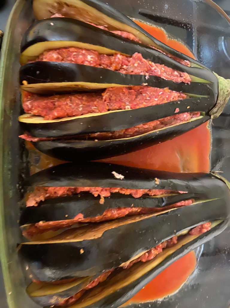 laying stuffed eggplants in sauce