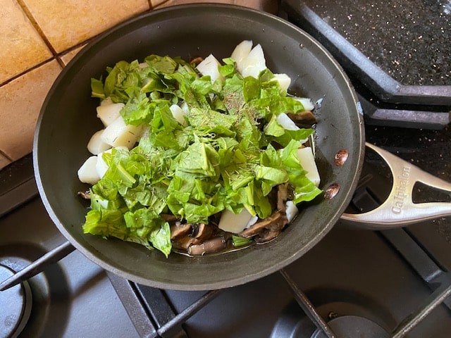 adding spinach to mushrooms onions and potatoes