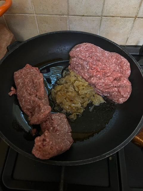 adding chopped beef to cooked onions