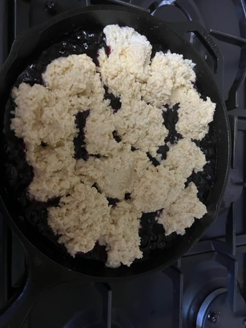 Mounding the biscuit dough on the blueberries