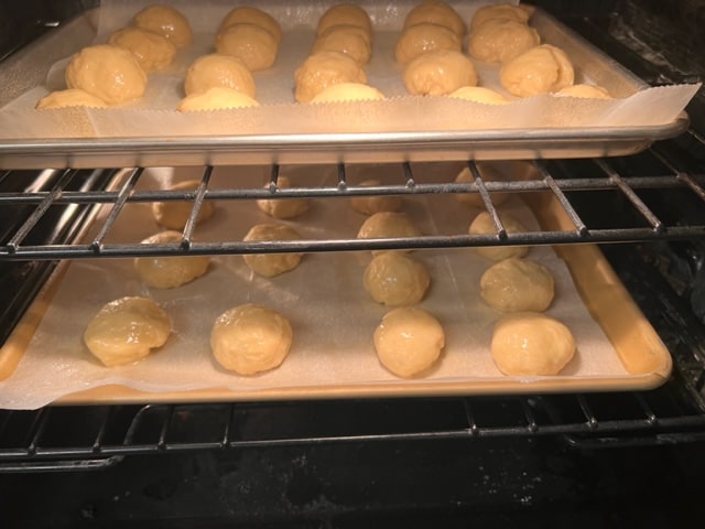 trays of doughnut balls rising in unheated oven