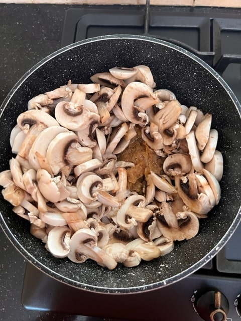 adding the mushrooms to the sauteed onions