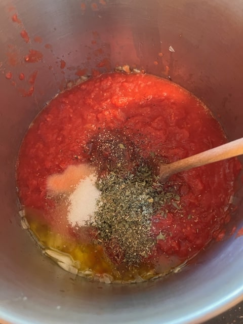 adding the spices and tomato paste and crushed tomatoes