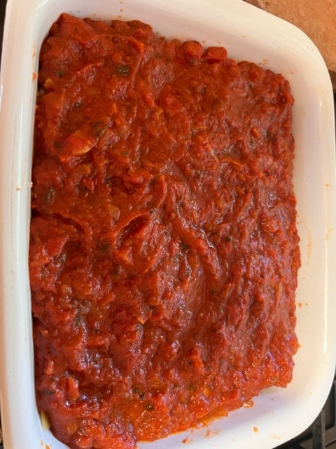 slathering sauce on last layer of noodles