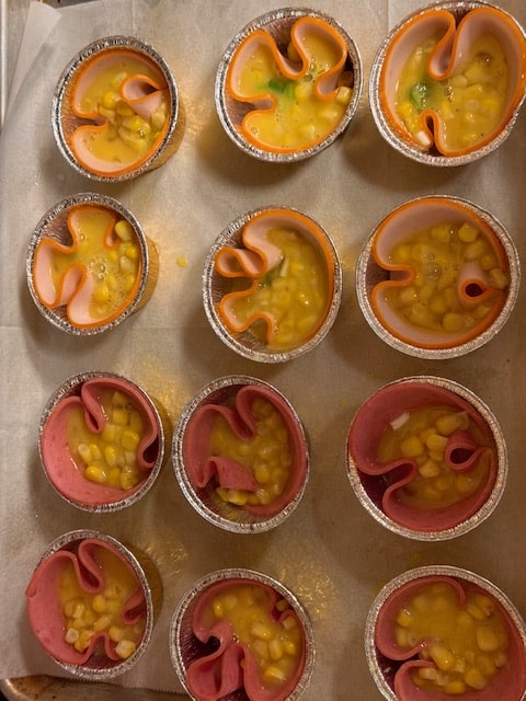 divide beaten egg between muffin tins