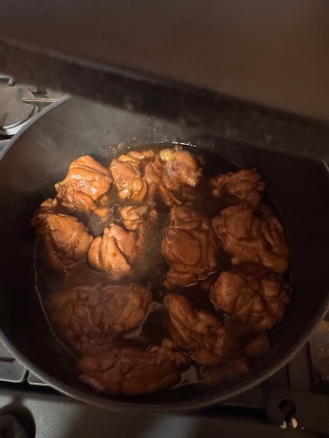 cooking chicken in sauce (note pot lid above)