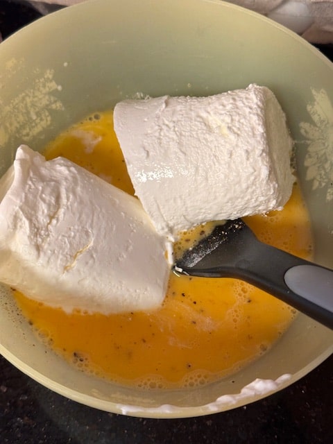 whisking egg, cream cheese and sour cream with spices