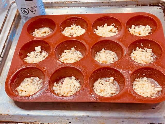 Place grated cheese in well greased muffin cups